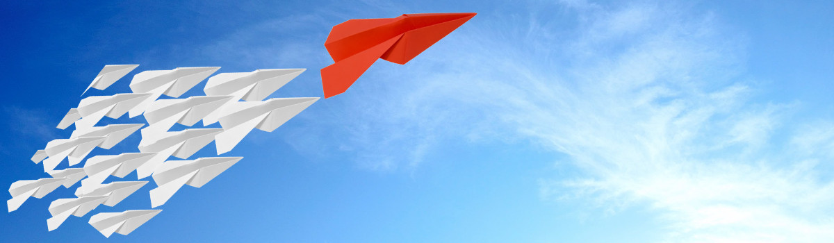 Group of paper airplanes against a blue sky, following one large red paper airplane